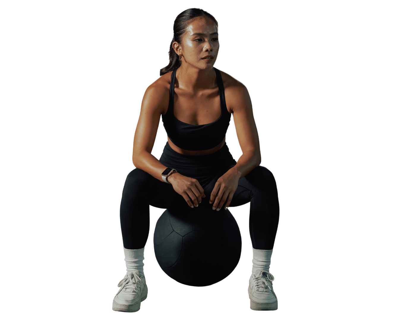 Mujer entrenadora de fitness sentada sobre balón medicinal, lista para entrenar, reflejando fuerza, enfoque y preparación.